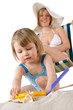 © CandyBox Images - Mother with child playing with beach toys