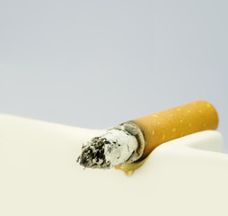 Cigarette burning in white ashtray