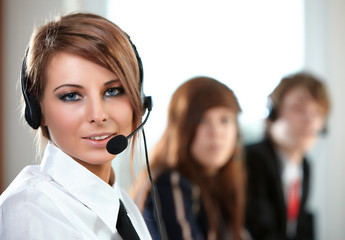 Beautiful representative smiling call center woman with headset.