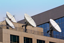 Four Satellite Dishes On Building Rooftop