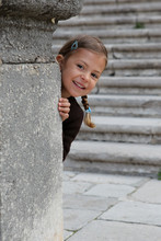 A Young Girl Enjoys Playing Peek A Boo From Behind A Pillar