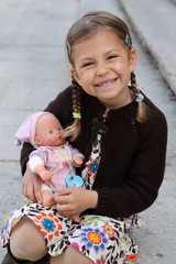pretty young girl cuddles and plays with her doll.