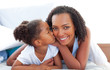© WavebreakMediaMicro - Loving little girl woman kissing her mother lying down on bed