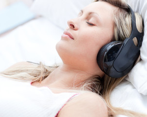 Canvas Print - Attractive woman with headphones on sleeping on a bed