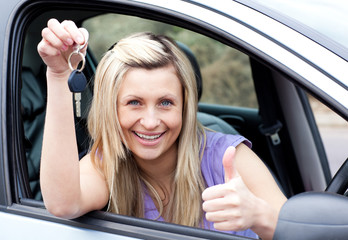 Charming female driver showing a key after bying a new car