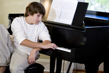 Serious Teenage Boy Looking Down At Piano Keys