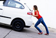 woman pushing car out of gasoline