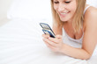 © WavebreakMediaMicro - Close-up of a woman sending a text lying on her bed