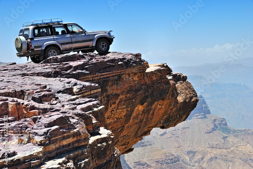 Naklejka ścienna Lone car is standing on rock over breakaway