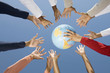 © Visual Ideas/Camilo Morales/Blend Images - Multi-ethnic hands reaching for globe ball