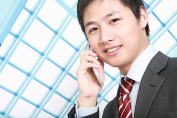 a businessman is standing  in office and answering the phone