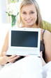 © WavebreakMediaMicro - Glowing woman showing a laptop sitting on a sofa