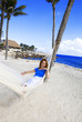 © Konstantin Kulikov - Young woman in hammock on background of palm trees and ocean..