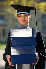 Wall Mural - Young female graduate with stack of boxes