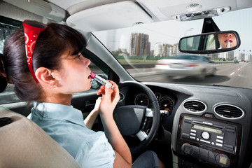 Driving a car, women make up lips at the wheel the car