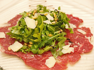 Poster - beef carpaccio with salad on a plate, white background