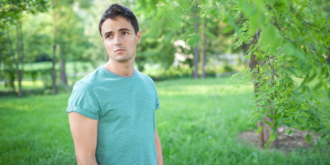 Portrait of a handsome young man while outdoors in a park on a l