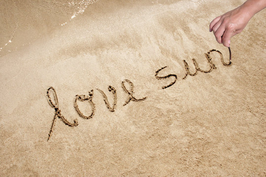 Love sun handwritten in sand on a a beach