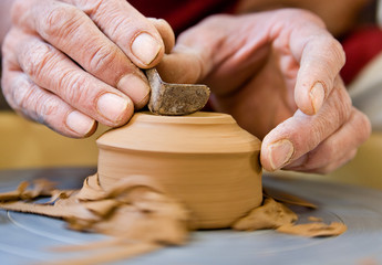 Potter shaping  the bottom of a cup on a spinning