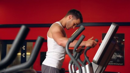 Wall Mural - Handsome sporty man is exercising in gym centre