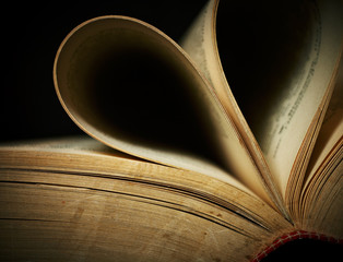 Close-up of opened old book against black background.