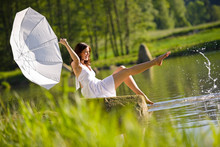 Happy Romantic Woman Sitting By Lake Splashing Water