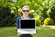 © FilipWarulik - Young blonde woman with computer in the garden