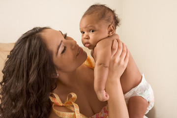 Wall Mural - Latina mother playing with her baby boy son on bed