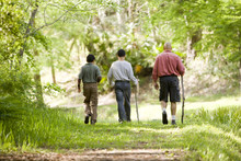 Hispanic Father And Sons Hiking On Trail In Woods