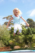 © Monkey Business - Young Girl Jumping On Trampoline In Garden