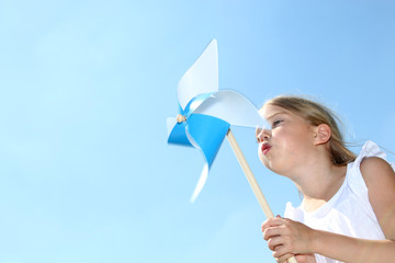 Closeup of little girl blowing blue wind wheel