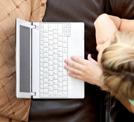 Canvas Print - Close up of a blond woman using a laptop lying on a sofa