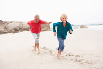 Wall Mural - Grandfather Chasing Grandson Along Winter Beach