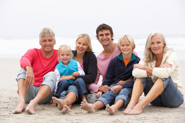 Wall Mural - Three Generation Family Sitting On Winter Beach Together