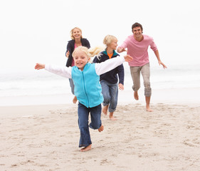 Wall Mural - Young Family Running Along Winter Beach