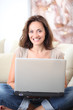 © goodluz - Woman on couch with laptop computer