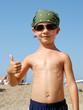 A little boy wearing sunglasses and bandanna shows OK