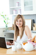 © WavebreakMediaMicro - Smiling woman having breakfast in front of the laptop