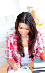 Merry female asian student doing math in the kitchen