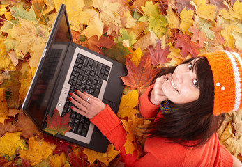 Wall Mural - girl in autumn orange leaves with laptop.