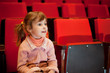 © Pavel Losevsky - Smiling little girl sitting on armchairs at cinema