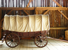 Covered Wagon In A Sunlit Rustic Barn