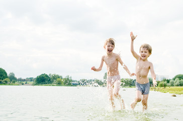 Little children making marry and playing in water with splashes