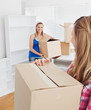 © WavebreakMediaMicro - Two smiling women carrying boxes at home