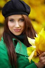 Wall Mural - Fashion woman in autumn park holding yellow leaf