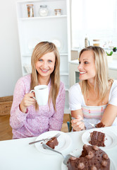 Wall Mural - Happy female friends eating a chocolate cake and drinking in the