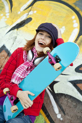 Sticker - Closeup portrait of a happy young girl with skateboard and graff