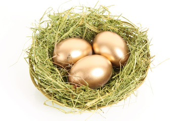 Wall Mural - Three golden hen's eggs in the grassy nest isolated on white