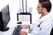 © get4net - male doctor working with desktop at his desk