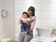 © Jim Esposito/Blend Images - Hispanic working mother holding baby son in home office